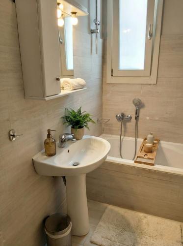 a bathroom with a sink and a bath tub with a mirror at Andros Guesthouses in Andros