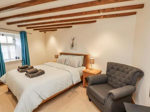 a bedroom with a bed and a chair at Chestnut Barn in Whitby