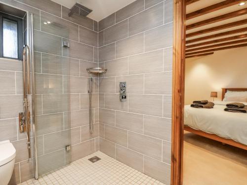 a bathroom with a shower with a toilet and a bed at Chestnut Barn in Whitby
