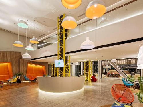 a lobby with orange and blue chairs and lights at ibis Styles Batam Nagoya in Nagoya