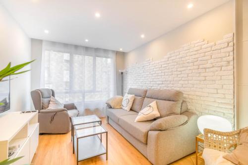a living room with a couch and a brick wall at Espacioso y cómodo apartamento en Pamplona in Barañáin
