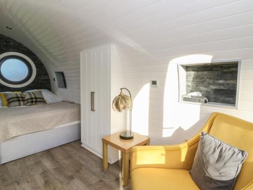 a bedroom with a bed and a chair and a table at Glamping Pod 5 - Gower in Swansea