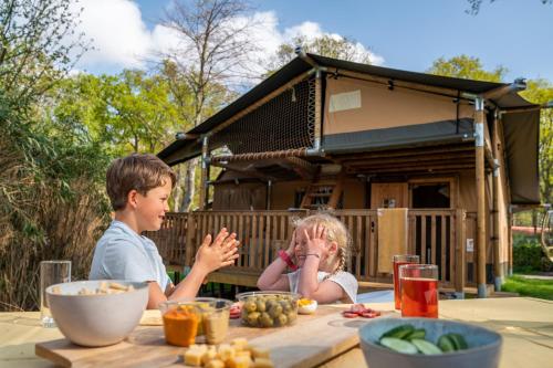 a boy and a girl sitting at a table with food at Familievakantiepark Krieghuusbelten in Raalte