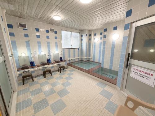 a bathroom with a tub and a sink and mirrors at Hotel Tetora HonHachinohe in Hachinohe