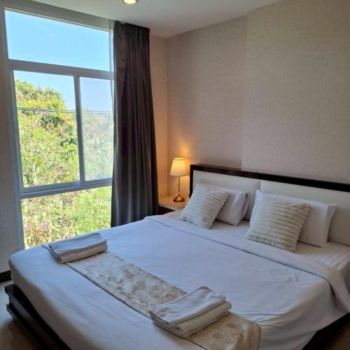 a bedroom with a large bed with a large window at Herry Residence in Chiang Mai