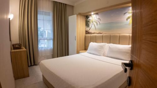 a bedroom with a white bed with a painting on the wall at Asya Blue Apartments in Marmaris