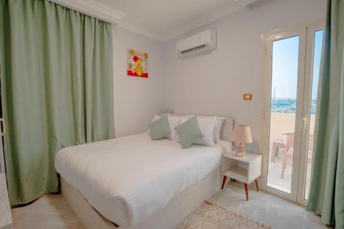 a white bedroom with a bed and a window at Sunshine Pyramids& Grand Museum View in Cairo