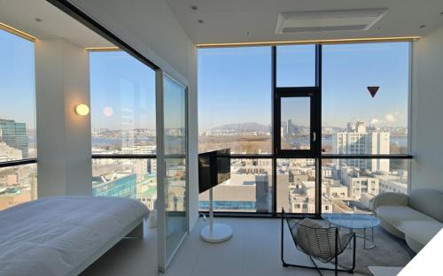 a bedroom with a bed and large glass windows at SunU Seoul Stay - All Rooms 45m Panoramic Han River View - 4m Ceiling in Seoul