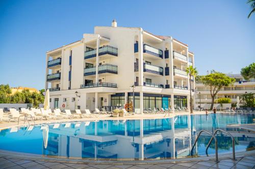 a hotel with a swimming pool in front of a building at Pins Platja Apartments in Cambrils