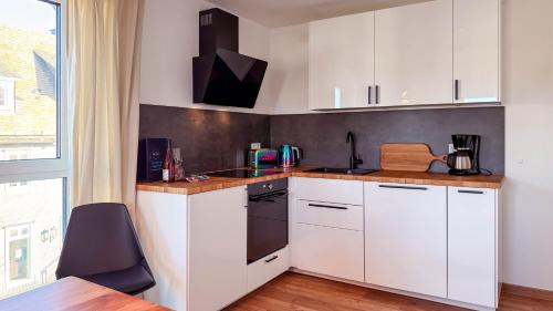 a kitchen with white cabinets and a black oven at Ferienwohnung CityVibes in Winterberg