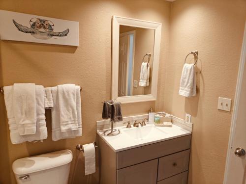 a bathroom with a sink and a toilet and a mirror at 2 Bd, Oceanfront Oasis, Lots of deals and Winter Texans book early in Galveston