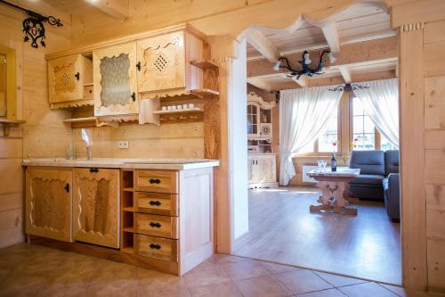 a kitchen with wooden cabinets and a living room at Smrekowy Dworek in Kościelisko