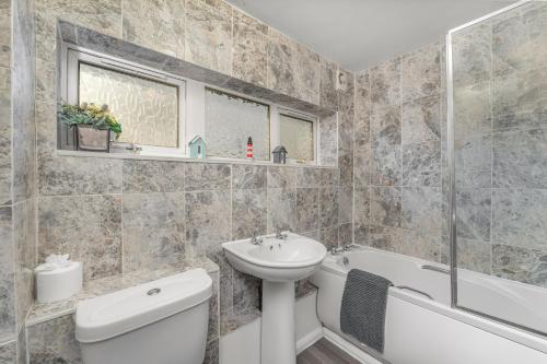 a bathroom with a sink and a toilet and a bath tub at Rabbit Haven- Near Bicester Village & Town - ShireStays in Bicester
