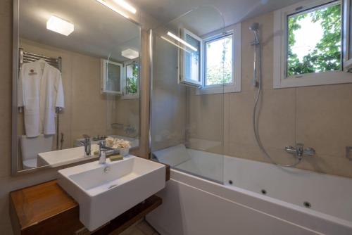 a bathroom with a sink and a tub and a shower at Rimondi Boutique Hotel - Small Luxury Hotels of the World in Rethymno