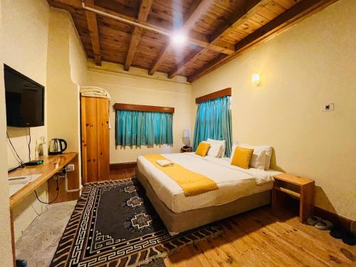a bedroom with a bed and a desk and a television at sinchula Villa Resort in Paro