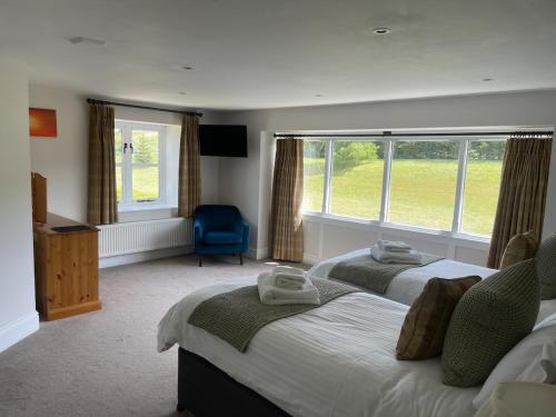 a bedroom with two beds and a blue chair at Cumberwell Cottages-Dash Corner in South Wraxall