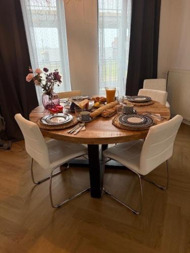 a wooden table with white chairs around it with food on it at center City appartement in Alphen aan den Rijn