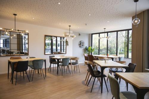 a dining room with tables and chairs and windows at Campanile PRIME - Troyes Nord Barberey in Troyes