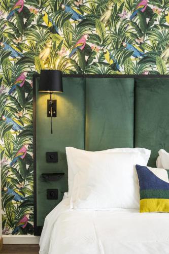 a bedroom with a bed with a tropical wallpaper at Campanile PRIME - Troyes Nord Barberey in Troyes