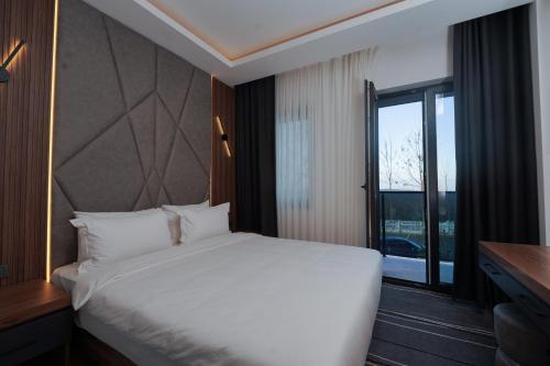 a bedroom with a white bed and a large window at Hotel Global Palace in Haskovo