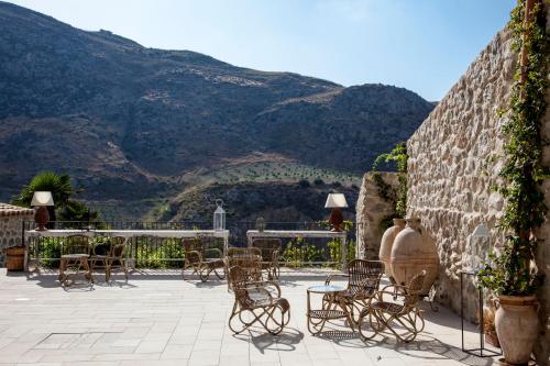a patio with chairs and tables with mountains in the background at Masseria Agnello in Realmonte