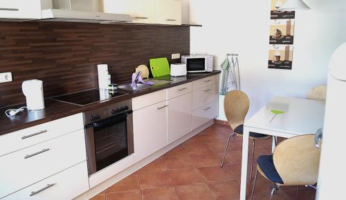 a kitchen with white cabinets and a table and a microwave at Ferienhaus Flora in Pirna