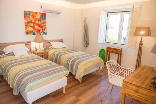 a bedroom with two beds and a table and a window at Casas dos Netos in Rio Maior