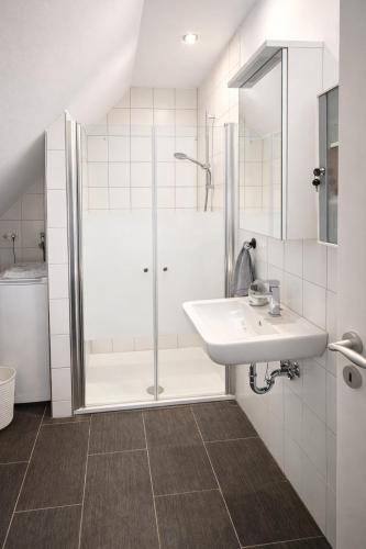 a white bathroom with a sink and a shower at Lysholm Living Luttmersen Ferienwohnung in Neustadt am Rübenberge