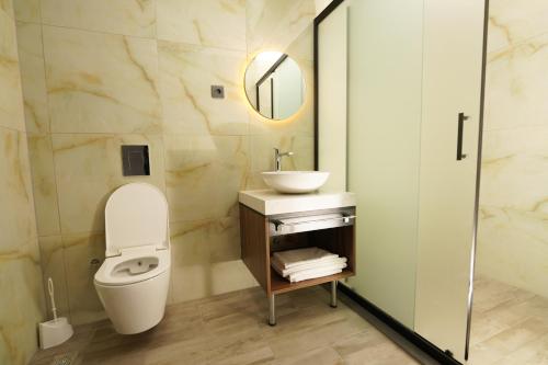 a bathroom with a toilet and a sink and a mirror at Hotel Global Palace in Haskovo