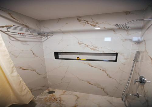 a bathroom with a shower and a marble wall at Suncrisp Studio Rooms in Pedda Waltair