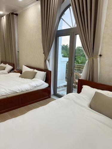 a bedroom with two beds and a large window at Huỳnh Thảo in Vũng Liêm