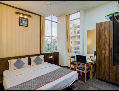 a bedroom with a bed and a desk and windows at Hotel MNG The Platinum in Kānpur