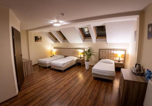 a large room with two beds and wooden floors at Zajazd Pod Borem in Pokój
