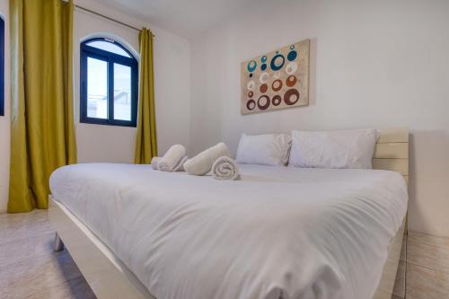a bedroom with a large white bed with yellow curtains at Budget Friendly apartment in Central Swieqi - 10 minutes walk to Paceville & the beach in St. Julianʼs