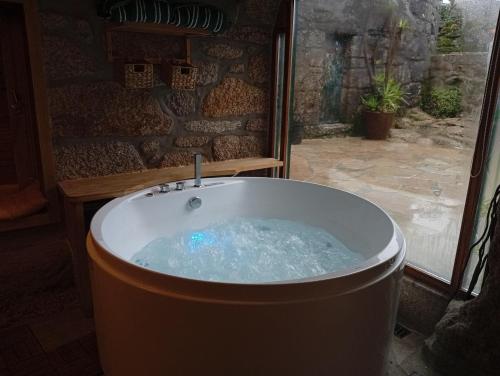 a bath tub in a room with a window at Casinha da Horta com Jacuzzi in Soajo