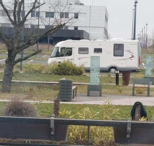 camping car في Saint-Georges-du-Bois: شاحنة بيضاء متوقفة بجوار حديقة بها مقاعد