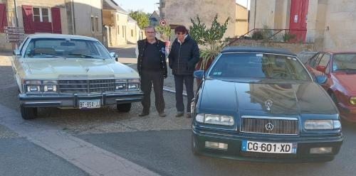 camping car في Saint-Georges-du-Bois: مجموعة من ثلاثة أشخاص يقفون بجوار سيارة زرقاء