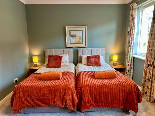 a bedroom with two beds with orange comforters at Bayfields house by the Sea, parking, garden, central location in Portsmouth
