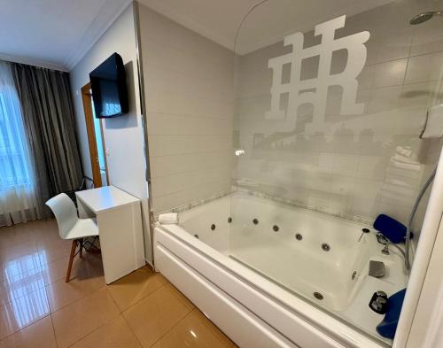 a bathroom with a tub and a table and a television at Hotel Reigosa in Pontevedra