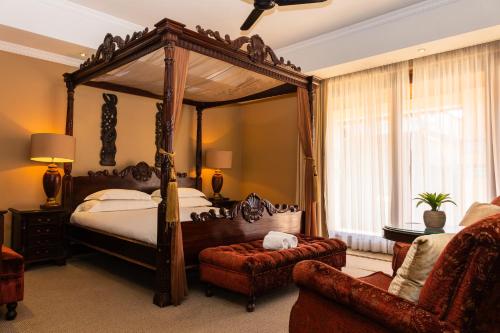 a bedroom with a canopy bed and a chair at Premier Hotel Anta Boga in Bloemfontein