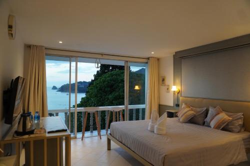 a bedroom with a bed and a balcony with a view at Residy Hideaway in Patong Beach