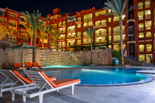 Sun & Sea Hotel and Aqua Park - Hurghada في الغردقة: مسبح وكراسي صالة ومبنى