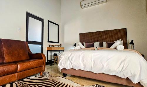 ein Schlafzimmer mit einem großen Bett und einem Stuhl in der Unterkunft Kitchen51 Cottages in Keetmanshoop