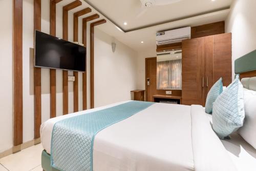 a bedroom with a white bed and a flat screen tv at FabHotel Prime The Oasis in Bhopal