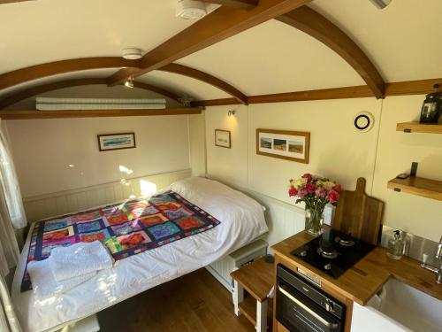 a small bedroom with a bed and a sink at Dartmoor Shepherds Hut at The Shrubbery, River Walkham, Horrabridge, Yelverton in Tavistock
