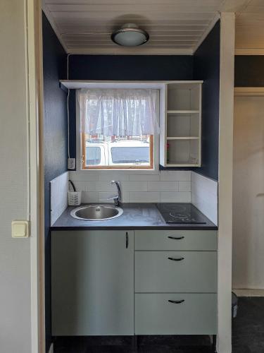 a small kitchen with a sink and a window at Strandbacka Stugor in Gnisvärd