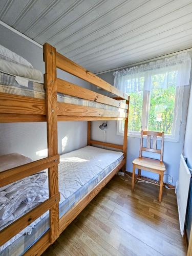 a bedroom with two bunk beds and a chair at Strandbacka Stugor in Gnisvärd
