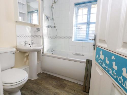 a bathroom with a toilet and a tub and a sink at Still Waters in Wyke Regis