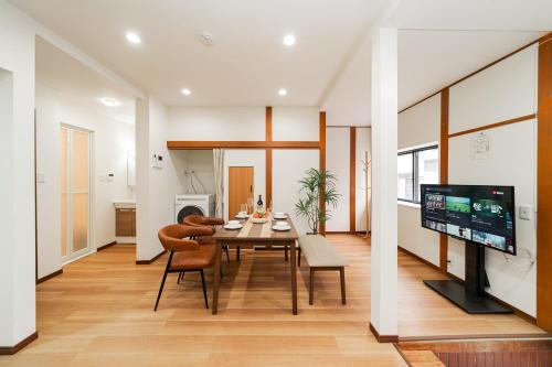 a dining room with a table and chairs and a television at NISHIKI Ryokan錦旅館 in Tokyo