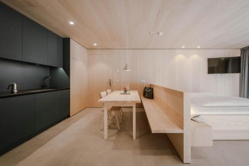 a kitchen with a table and a bed in a room at Kersh Dolomites Lodge in San Candido